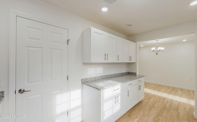 kitchen with white cabinets, an inviting chandelier, decorative light fixtures, and light hardwood / wood-style flooring