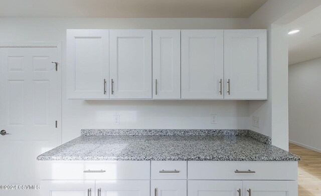 kitchen featuring light hardwood / wood-style floors, white cabinetry, and light stone counters