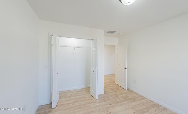 unfurnished bedroom with light wood-type flooring and a closet