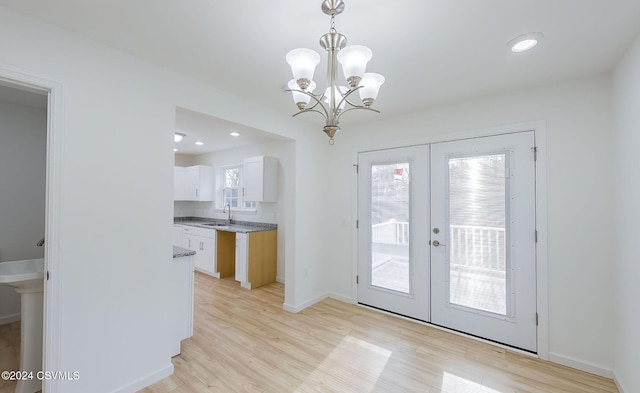 entryway with a chandelier, light hardwood / wood-style floors, a wealth of natural light, and french doors