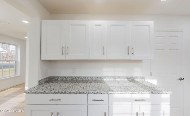 kitchen with light stone countertops, light hardwood / wood-style flooring, and white cabinets