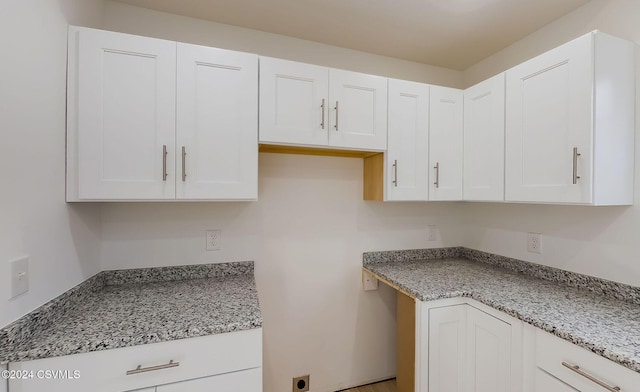 kitchen featuring light stone counters and white cabinets