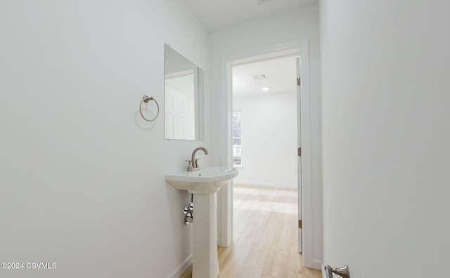 corridor with light hardwood / wood-style flooring and sink