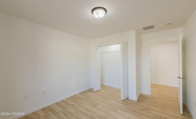 unfurnished bedroom with a closet and light hardwood / wood-style floors