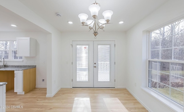 entryway featuring an inviting chandelier, light wood-type flooring, sink, and french doors