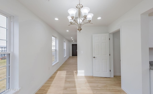 hall featuring a notable chandelier, a wealth of natural light, and light hardwood / wood-style flooring