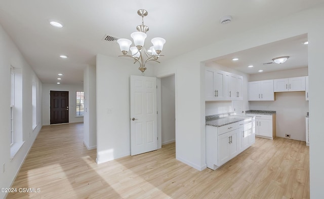 kitchen featuring white cabinets, stone countertops, pendant lighting, and light hardwood / wood-style flooring