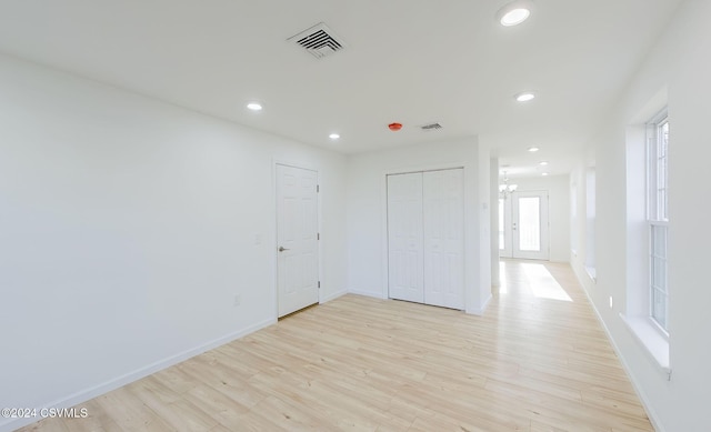 empty room with an inviting chandelier and light hardwood / wood-style flooring