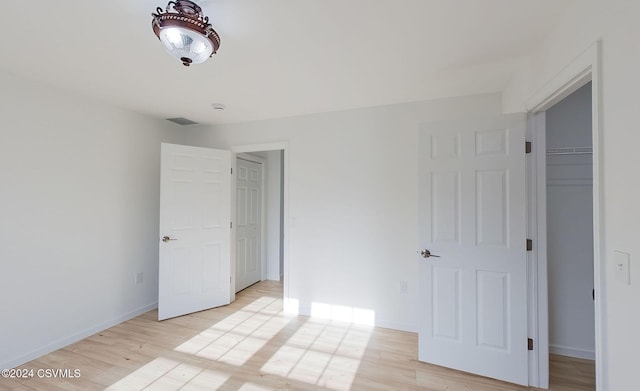 unfurnished bedroom featuring a walk in closet, light hardwood / wood-style flooring, and a closet