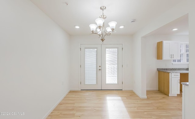 entryway with french doors, a notable chandelier, and light wood-type flooring