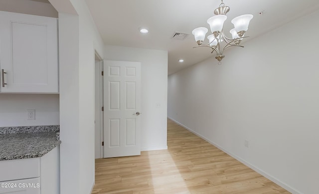 unfurnished dining area with a chandelier and light hardwood / wood-style flooring