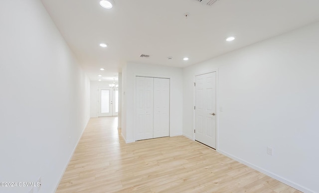 corridor with a chandelier and light wood-type flooring