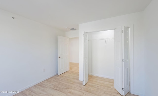 unfurnished bedroom featuring light wood-type flooring and a closet