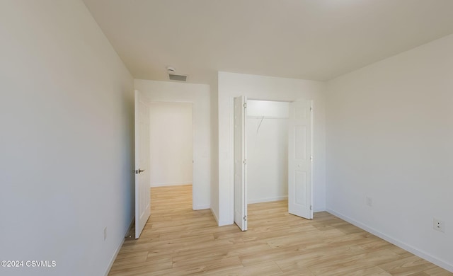 unfurnished bedroom with light wood-type flooring and a closet