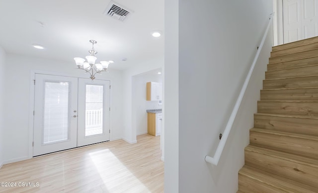 interior space featuring french doors, light wood-type flooring, and an inviting chandelier