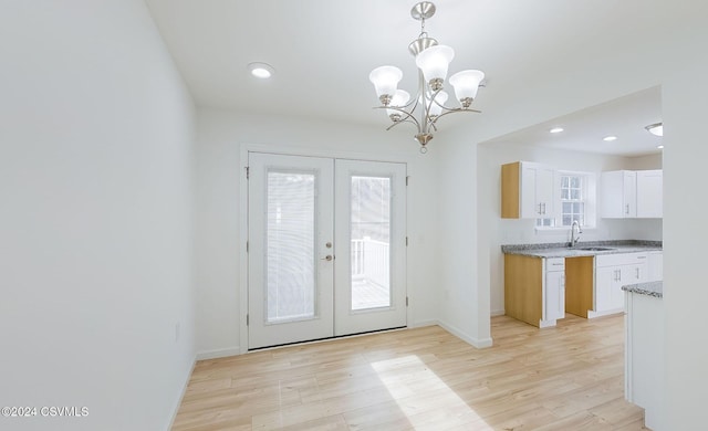 entryway featuring an inviting chandelier, light wood-type flooring, sink, and french doors