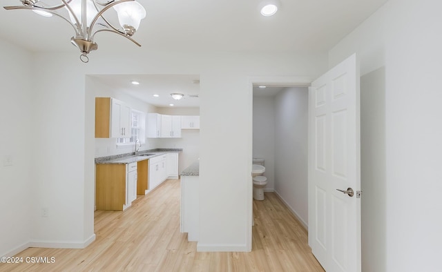 kitchen featuring sink, pendant lighting, light hardwood / wood-style flooring, a notable chandelier, and white cabinetry