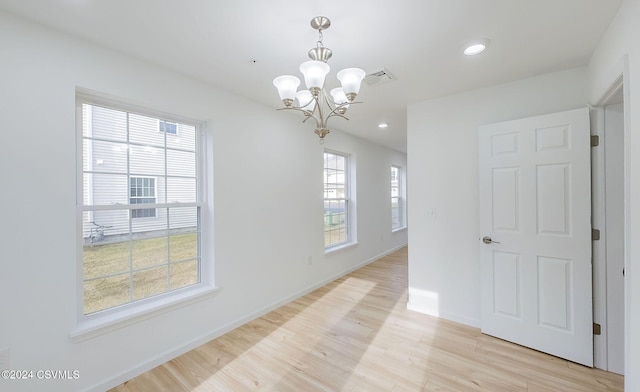 interior space with light wood-type flooring, an inviting chandelier, and plenty of natural light