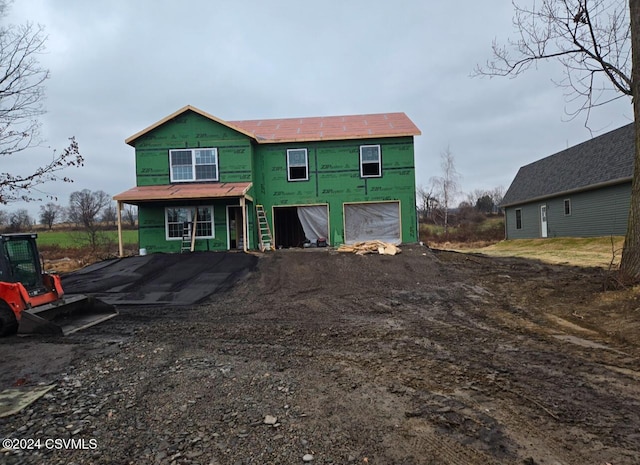 unfinished property with a garage and dirt driveway