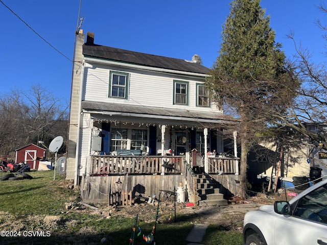 view of front of home featuring a porch and a storage shed