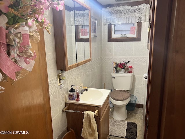 bathroom with tile patterned floors, vanity, toilet, and tile walls