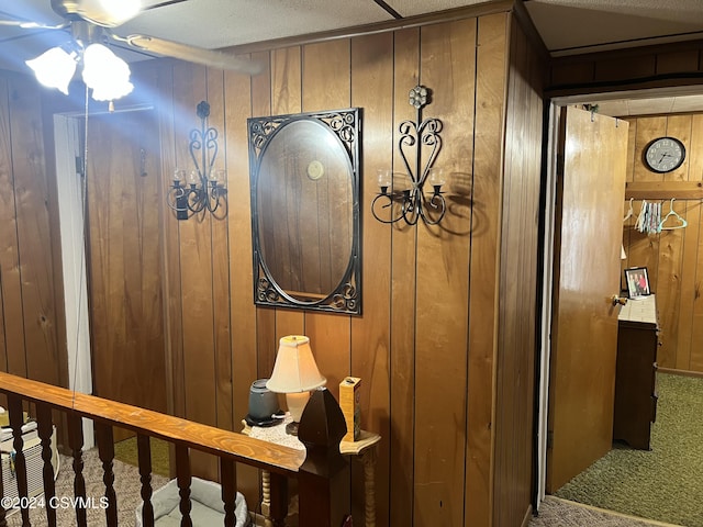 room details featuring carpet flooring, a textured ceiling, and wooden walls