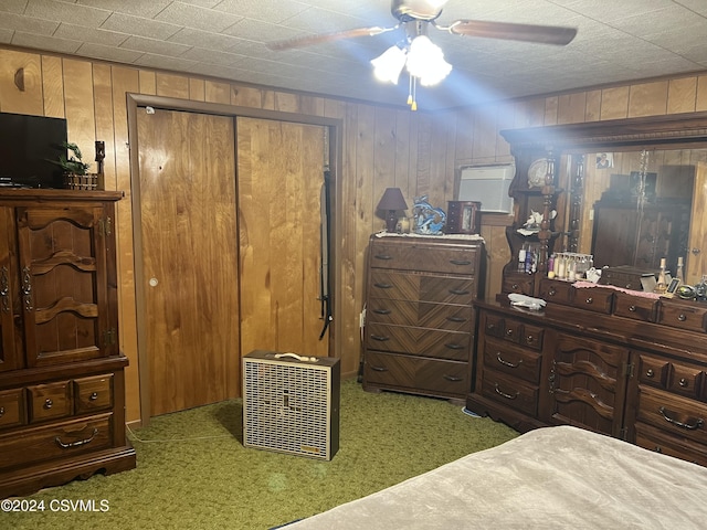 bedroom with carpet, ceiling fan, wooden walls, and a closet