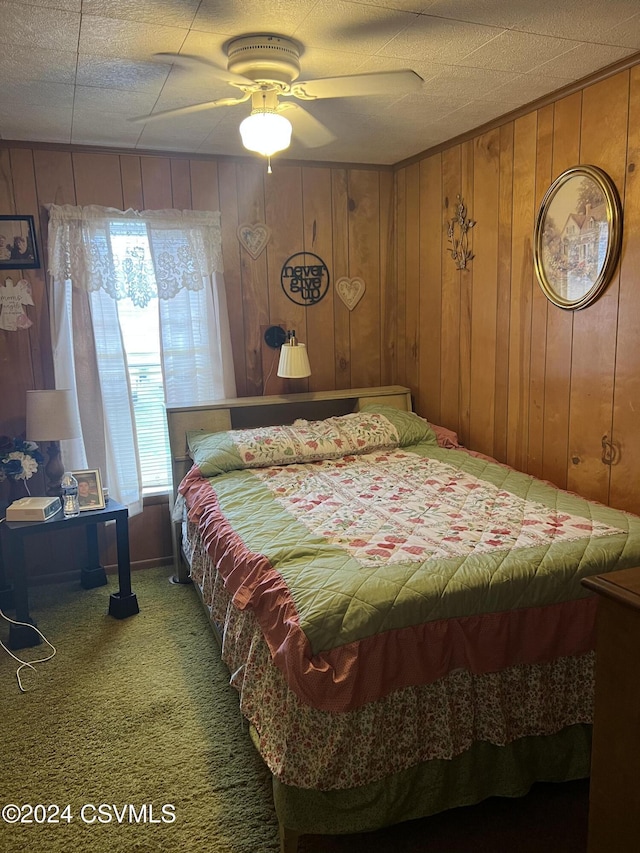 bedroom with carpet floors, ceiling fan, and wooden walls