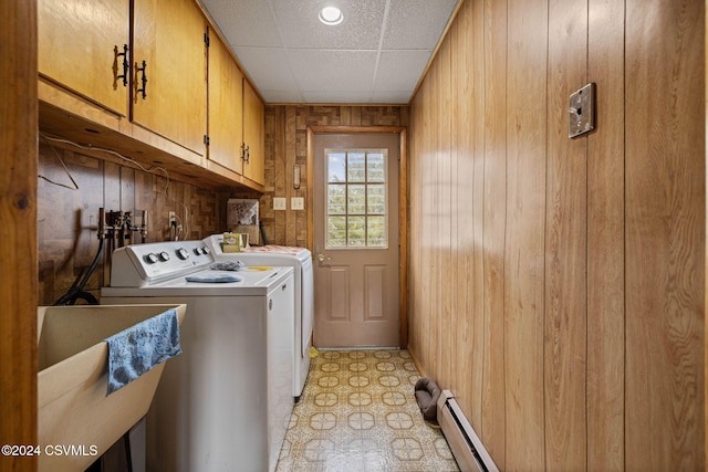 laundry room with cabinets, sink, wooden walls, washing machine and dryer, and baseboard heating