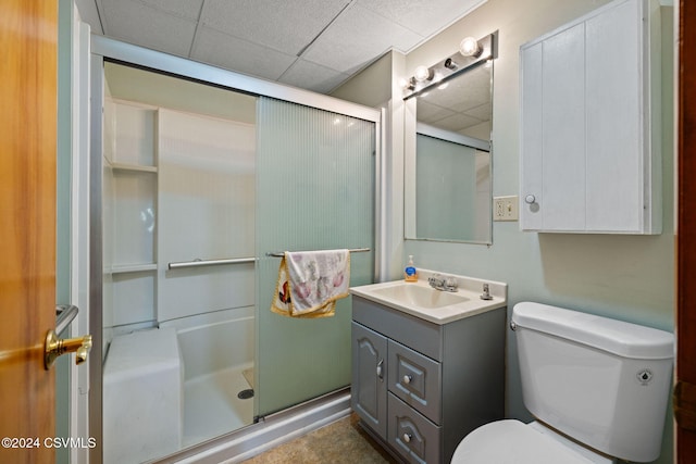 bathroom with a paneled ceiling, toilet, vanity, and walk in shower