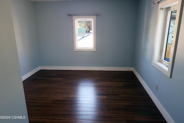 unfurnished room with dark hardwood / wood-style flooring and a healthy amount of sunlight