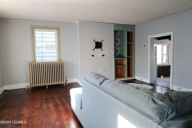 living room featuring radiator, dark wood-type flooring, and a textured ceiling