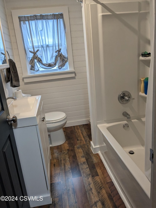 full bathroom featuring wood-type flooring, toilet, wooden walls, vanity, and shower / bathtub combination