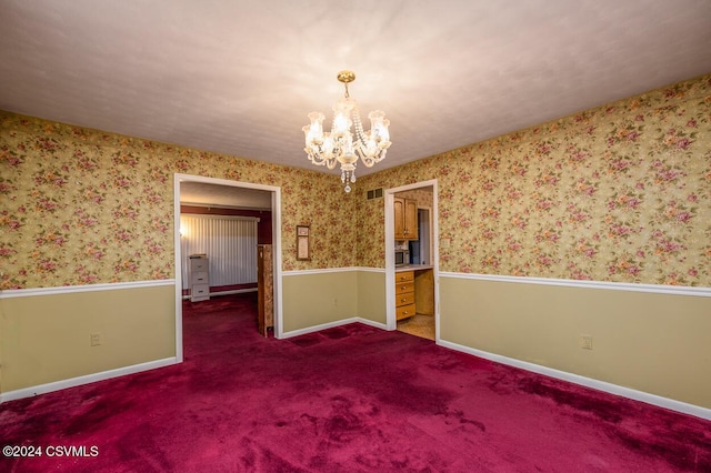 carpeted empty room featuring a chandelier