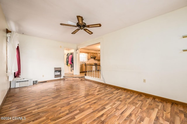 spare room featuring hardwood / wood-style floors, ceiling fan, a wall mounted AC, and heating unit