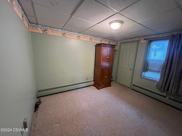 unfurnished bedroom featuring baseboard heating, a drop ceiling, and carpet