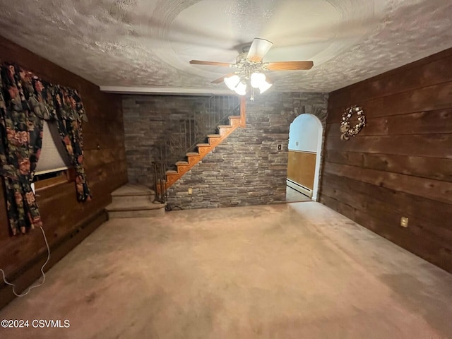 basement with wood walls, ceiling fan, and a textured ceiling