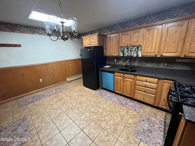 kitchen with baseboard heating, wooden walls, sink, black appliances, and an inviting chandelier