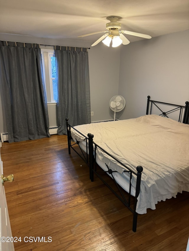 bedroom featuring baseboard heating, ceiling fan, and dark wood-type flooring