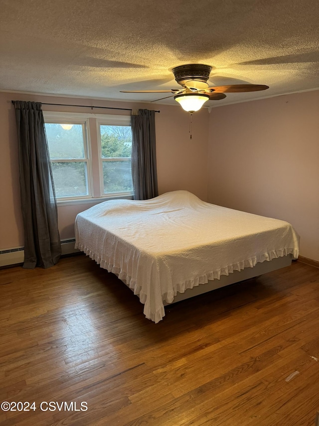 bedroom with baseboard heating, ceiling fan, a textured ceiling, and hardwood / wood-style flooring