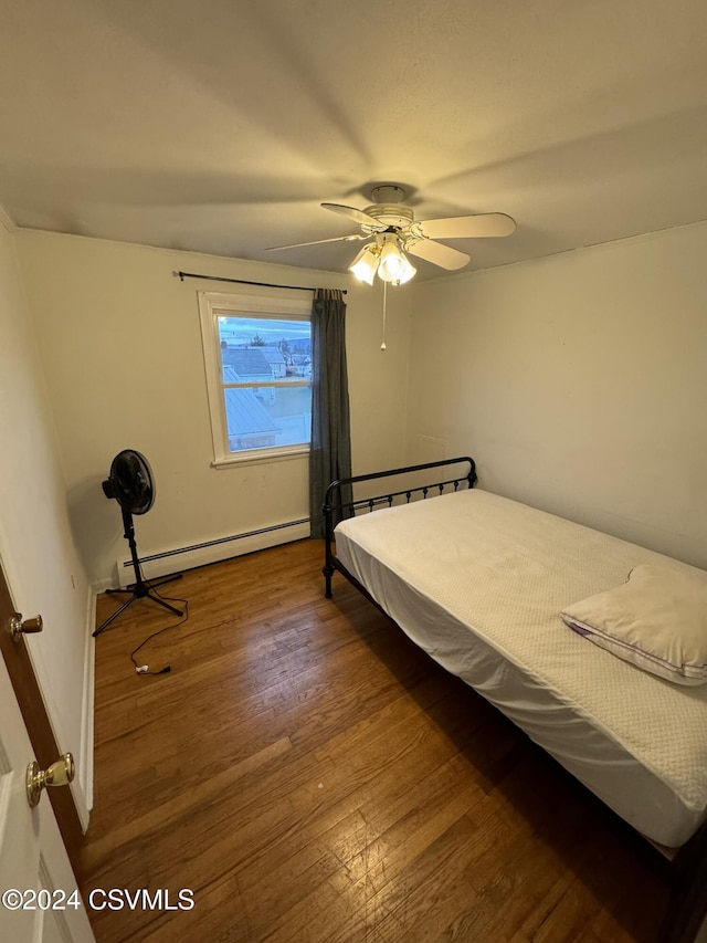 bedroom featuring baseboard heating, ceiling fan, and dark wood-type flooring