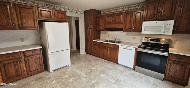 kitchen with dark brown cabinetry, white appliances, and sink