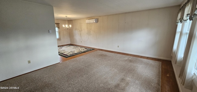 unfurnished room with a wall mounted air conditioner, dark hardwood / wood-style flooring, and an inviting chandelier