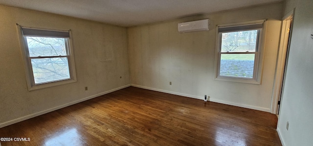 unfurnished room with a wall mounted air conditioner and dark hardwood / wood-style floors