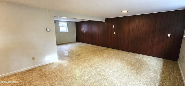 spare room featuring beamed ceiling, light carpet, and wooden walls