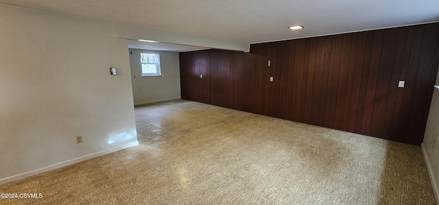 unfurnished room with beamed ceiling, light colored carpet, and wooden walls