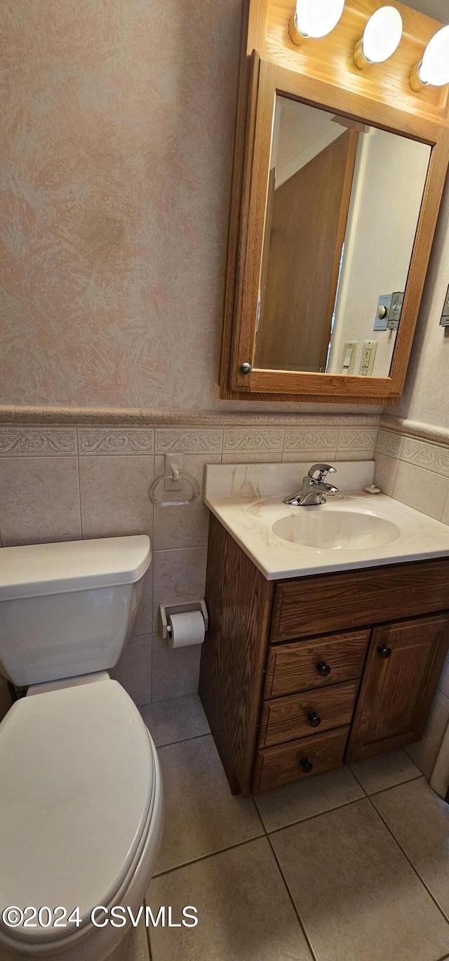 bathroom featuring tile patterned floors, vanity, tile walls, and toilet