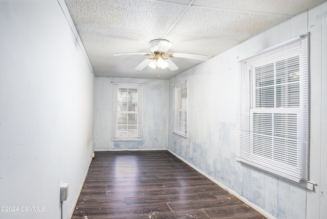 unfurnished room featuring a paneled ceiling, ceiling fan, and dark wood-type flooring