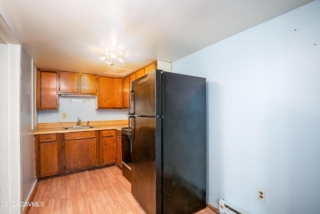 kitchen with sink, black appliances, a baseboard heating unit, and light hardwood / wood-style floors