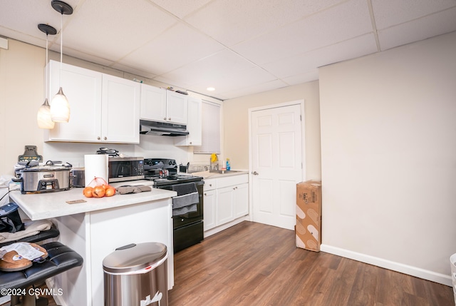 kitchen with a paneled ceiling, black electric range oven, white cabinets, and pendant lighting